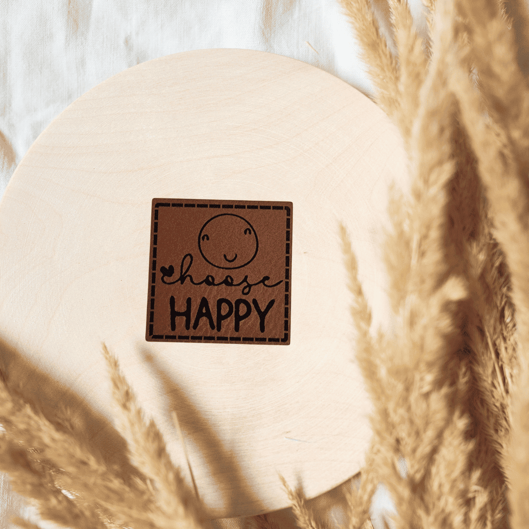 Quadratisches braunes Kunstleder-Label mit dem Schriftzug „Choose Happy“, 4 x 4 cm, veganes Nählabel für gute Laune und Kleidung, laser-graviert bei Schnuckidu.