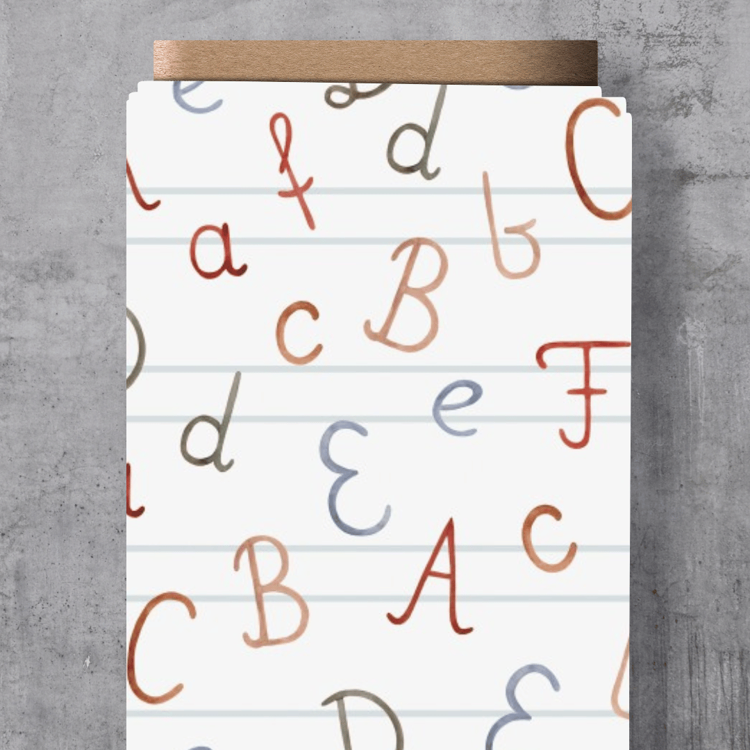 Weicher Kinderstoff mit einem modernen Allover-Muster aus verspielten Buchstaben von A bis Z in Weiß und Grau auf einem hellgrau melierten Hintergrund.
