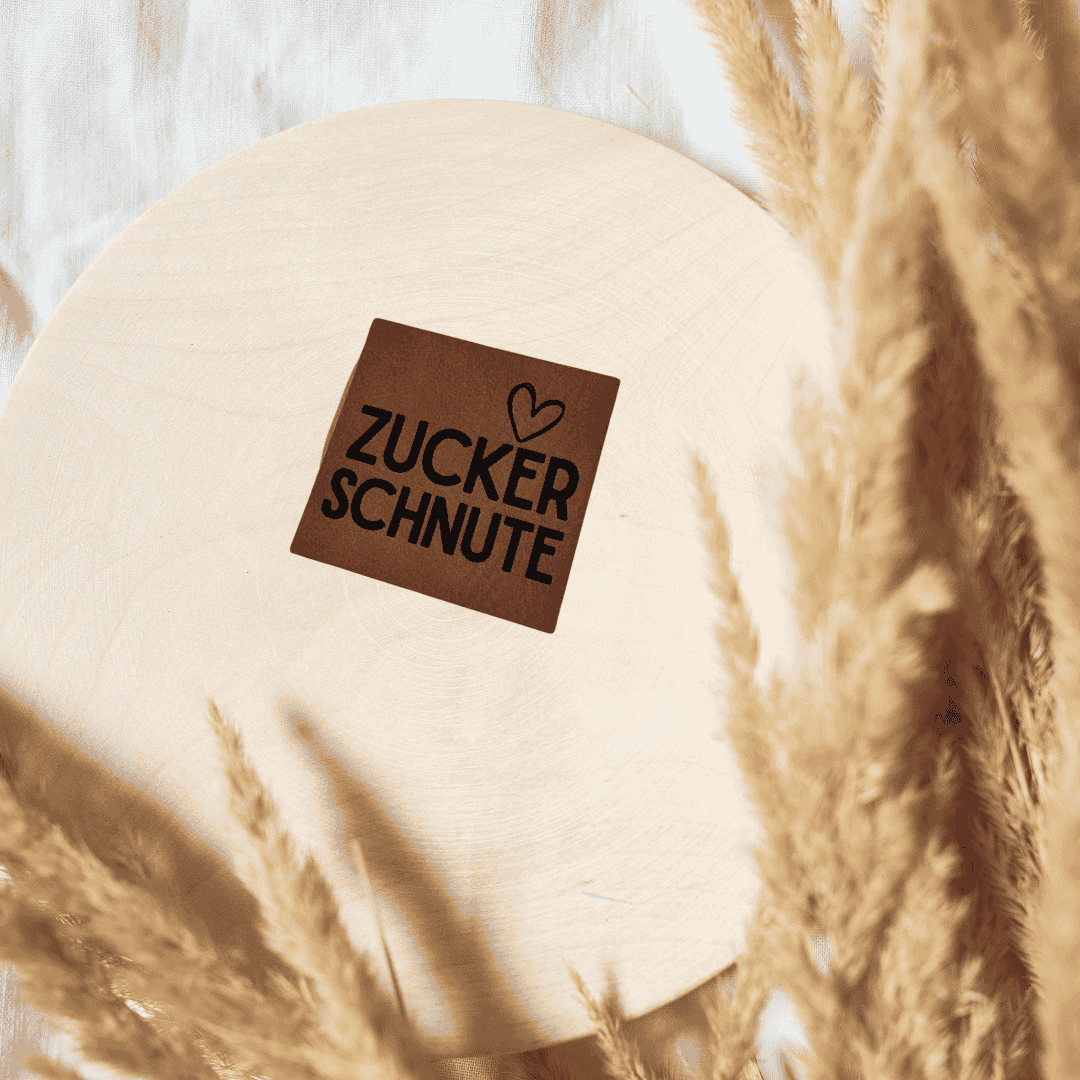 Quadratisches braunes Kunstleder-Label mit dem Schriftzug „Zuckerschnute“, 4 x 4 cm, veganes Nählabel für süße Baby- und Kinderkleidung, laser-graviert bei Schnuckidu.