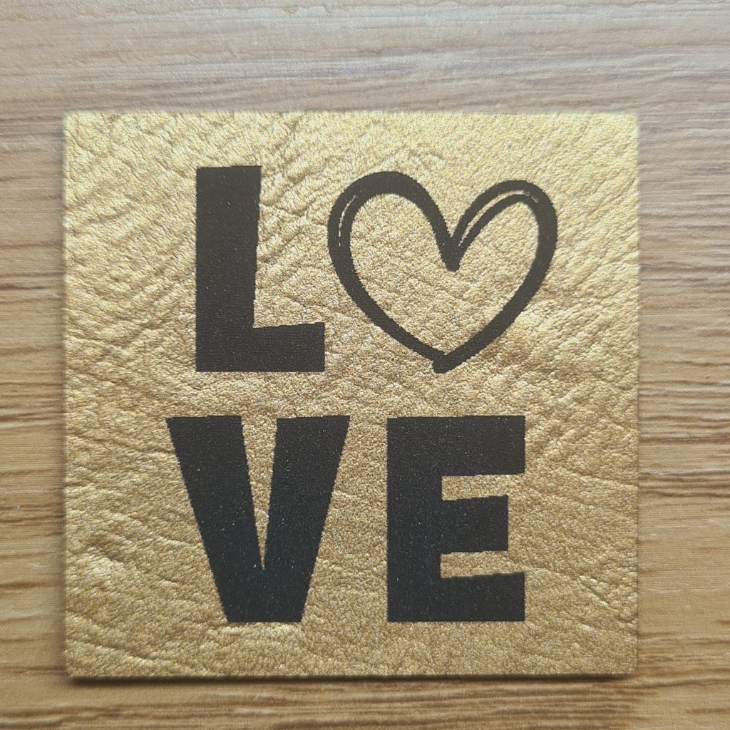 Quadratisches goldenes Kunstleder-Label mit dem Schriftzug „L❤VE“, ca. 4 x 4 cm, veganes Leder-Patch in Metallic-Optik mit Herz-Symbol, laser-graviert bei Schnuckidu