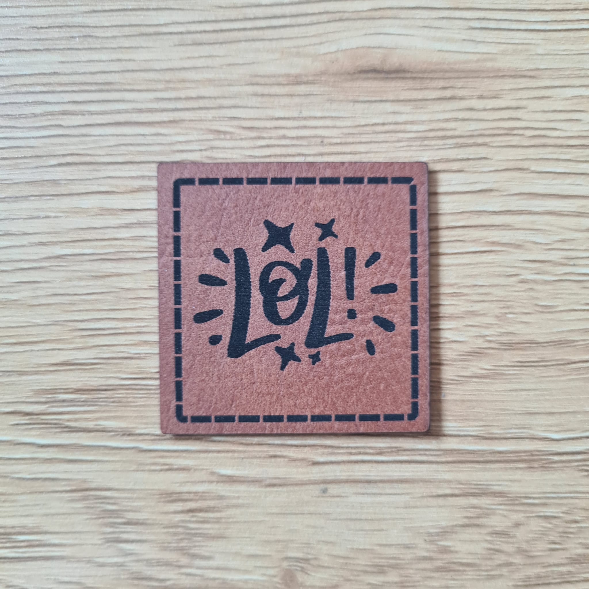 Quadratisches braunes Kunstleder-Label mit dem Schriftzug „LOL“, 4 x 4 cm, veganes Nählabel für Streetwear und Accessoires, laser-graviert bei Schnuckidu
