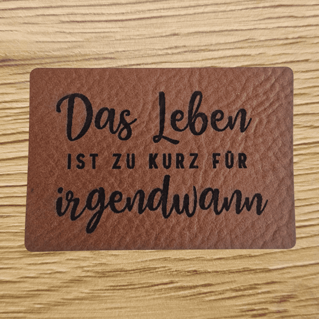 Rechteckiges braunes Kunstleder-Label mit dem gravierten Spruch „Das Leben ist zu kurz für irgendwann“, 5,0 x 3,3 cm, veganes Nählabel für Kleidung und Taschen, laser-graviert bei Schnuckidu.