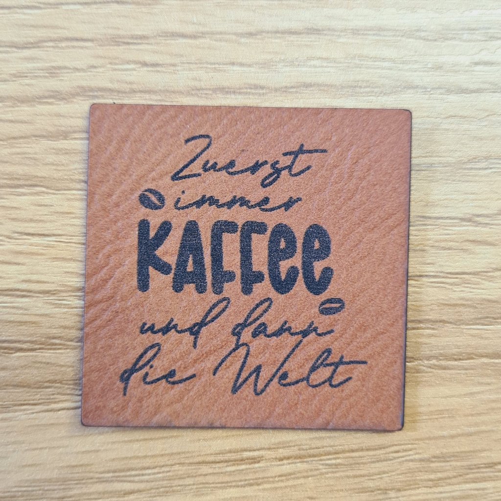 Quadratisches braunes Kunstleder-Label mit dem Spruch „Zuerst immer Kaffee und dann die Welt“, ca. 4 x 4 cm, veganes Leder-Patch für Kaffeeliebhaber, laser-graviert bei Schnuckidu