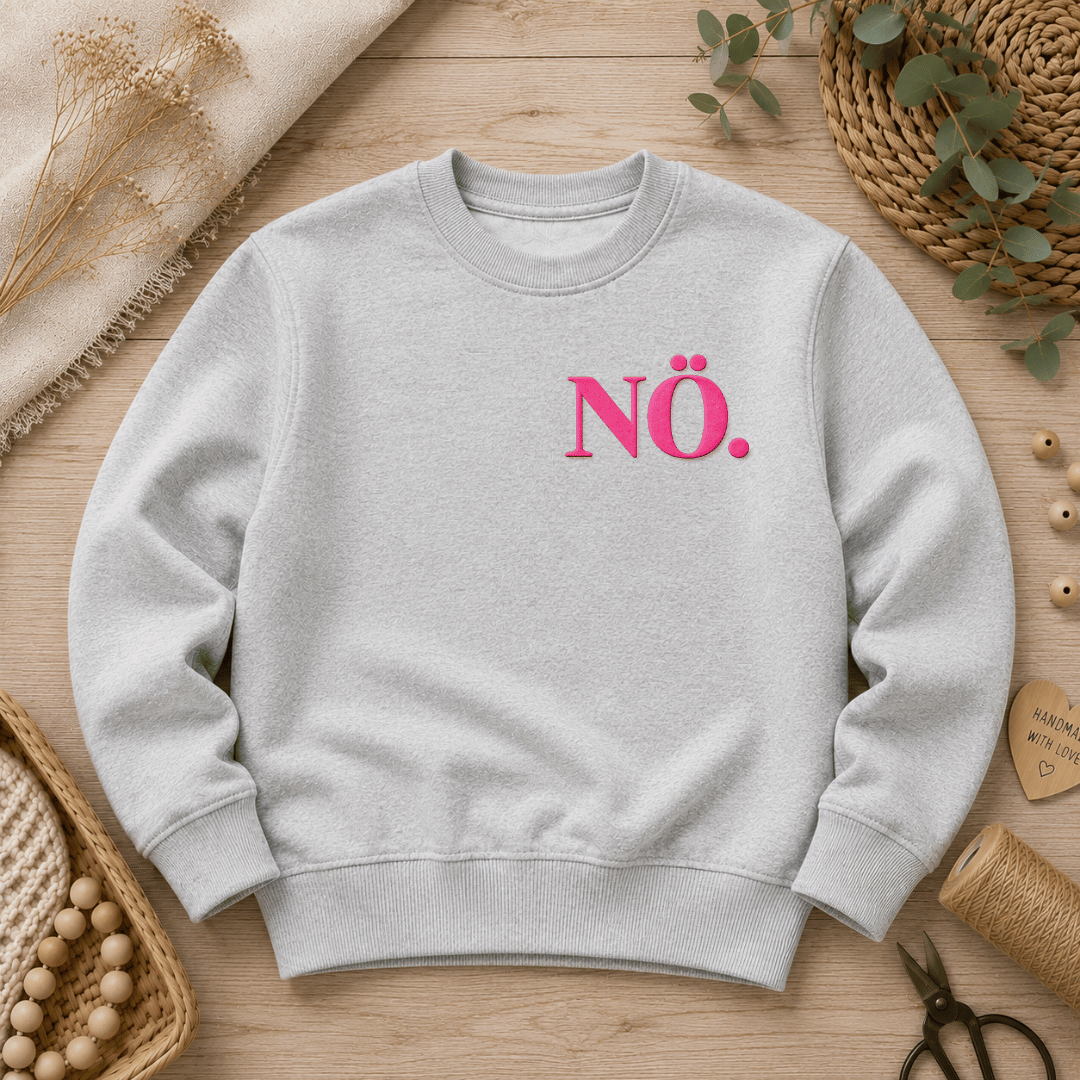 Flauschiges Flock-Patch mit dem Schriftzug Nö. in Neon-Pink aufgebügelt auf der Brust eines grauen Sweatshirts.