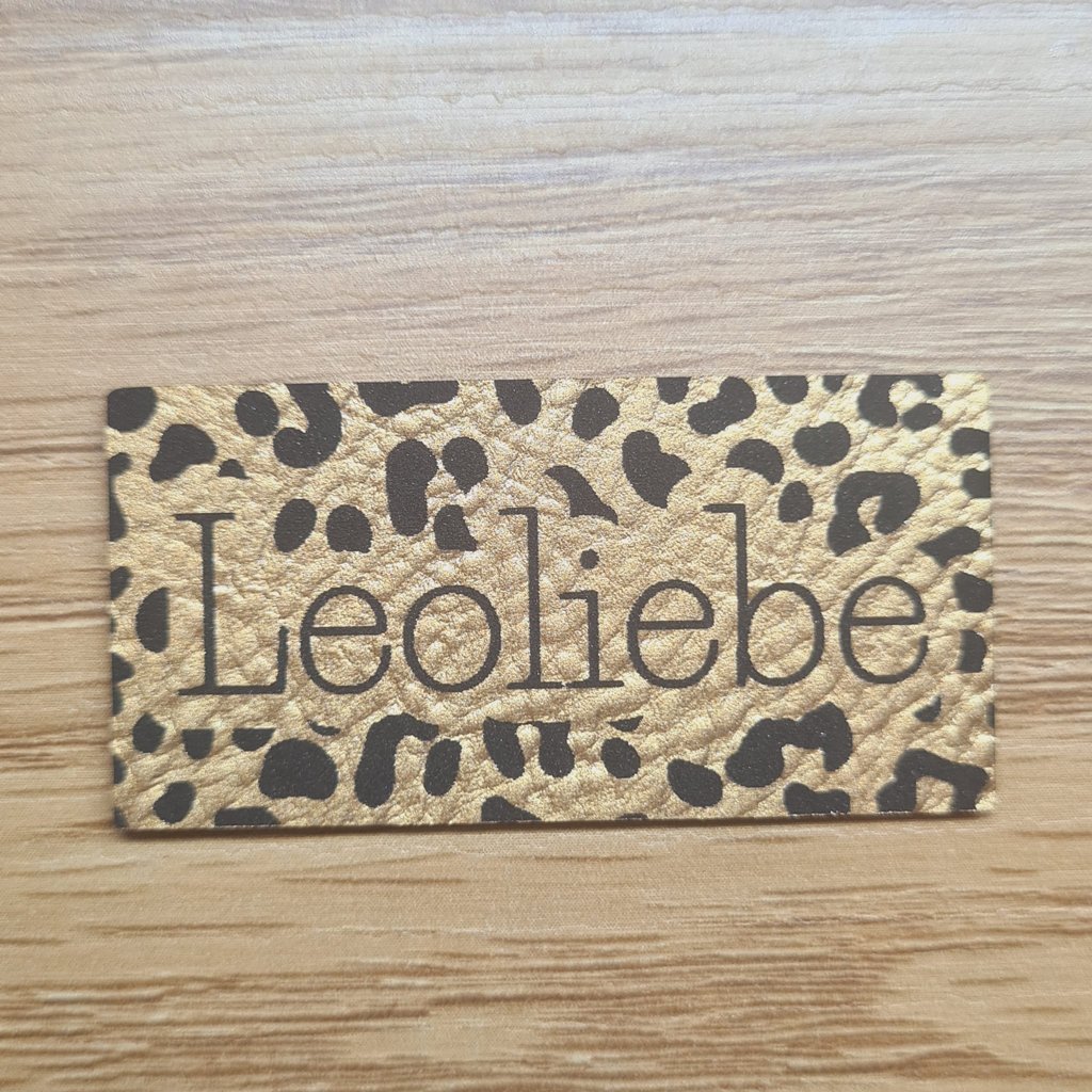 Rechteckiges goldenes Kunstleder-Label mit dem Schriftzug „Leoliebe“, ca. 5 x 2,5 cm, veganes Leder-Patch in Metallic-Optik, laser-graviert bei Schnuckidu