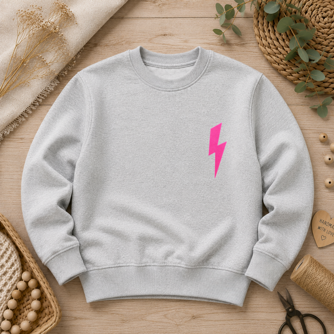 Samtiges Flock-Patch in Form eines vertikalen Blitzes in Neon-Pink aufgebügelt auf der Brust eines grauen Sweatshirts.