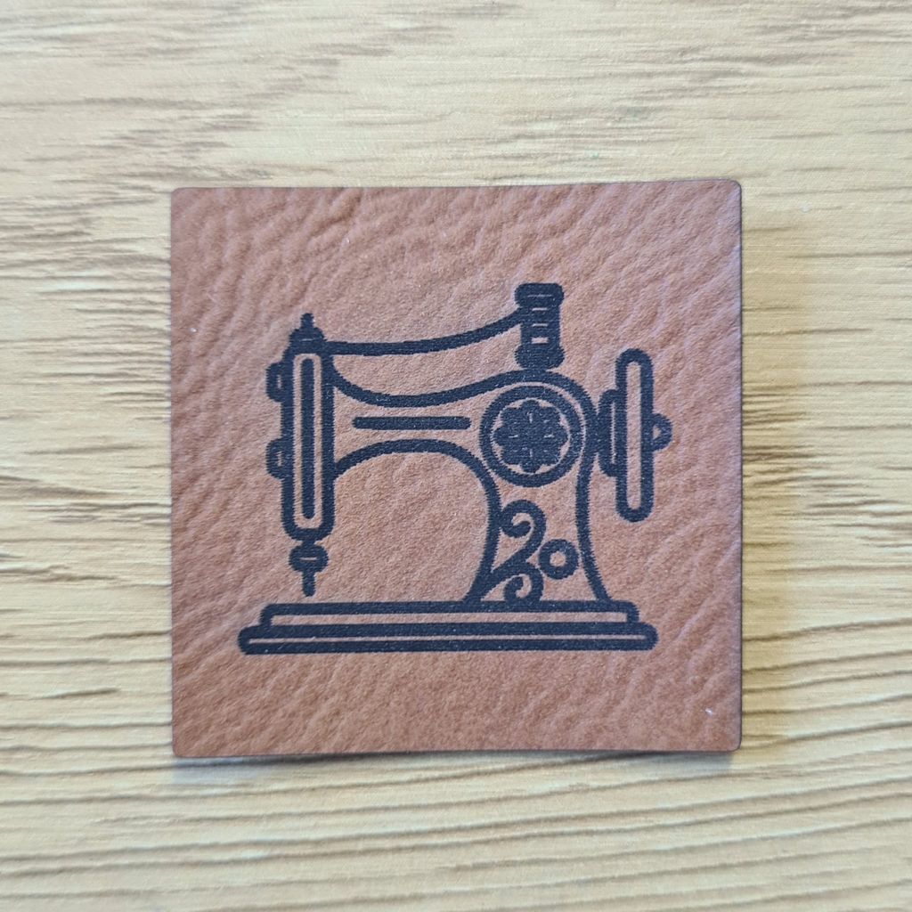 Quadratisches braunes Kunstleder-Label mit einem detailreichen Nähmaschinen-Motiv, 4 x 4 cm, veganes Nählabel im klassischen Leder-Look für Handmade-Projekte, laser-graviert bei Schnuckidu.