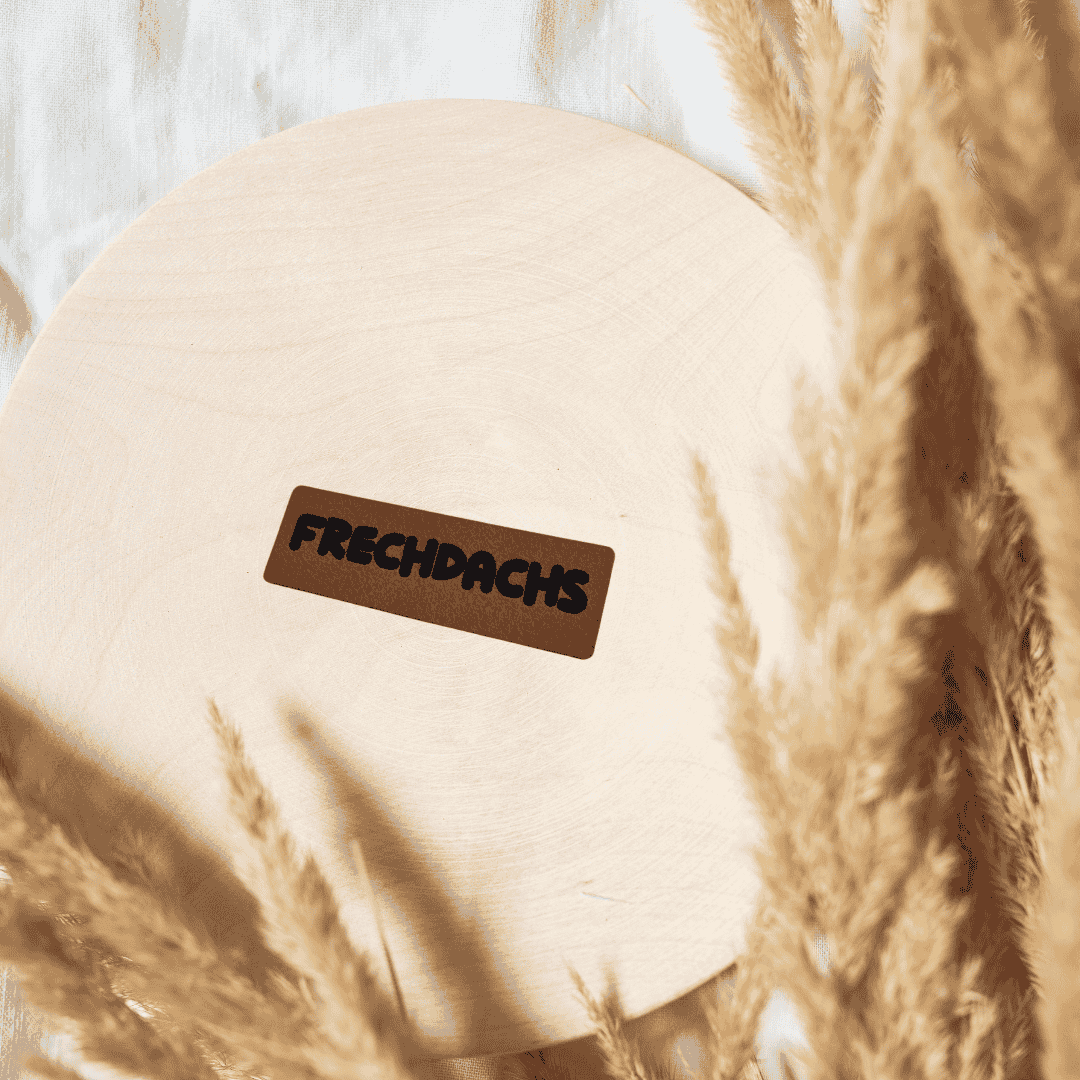 Schmales, rechteckiges braunes Kunstleder-Label mit dem Schriftzug „Frechdachs“, 4,2 x 1,3 cm, veganes Nählabel für coole Kinderkleidung, laser-graviert bei Schnuckidu.