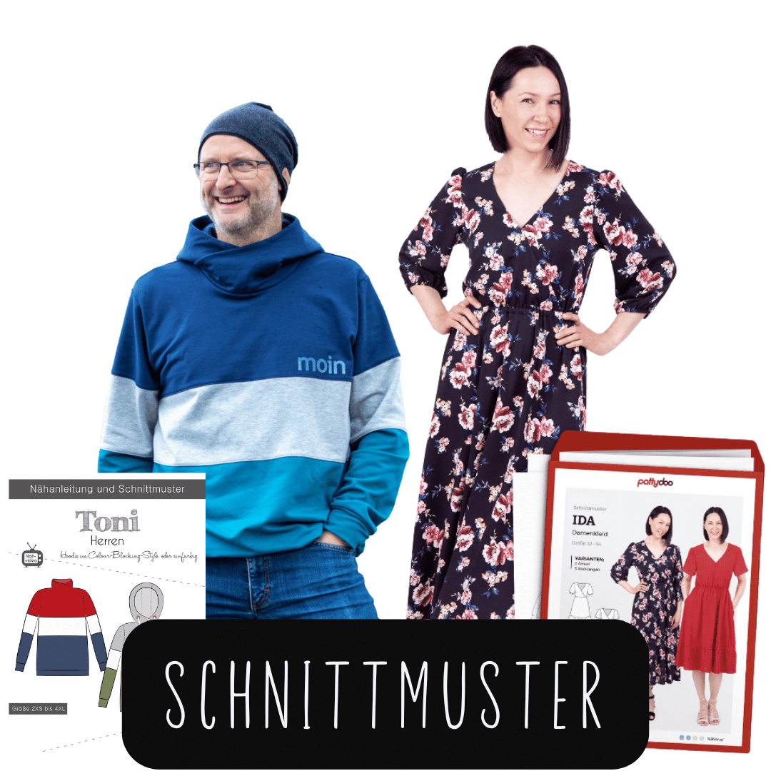 Zwei Personen stehen nebeneinander, eine trägt einen blau-grauen Kapuzenpullover, die andere ein langes, geblümtes Kleid, davor liegen zwei Schnittmusterverpackungen mit Abbildungen von Kleidungsstücken und Texten