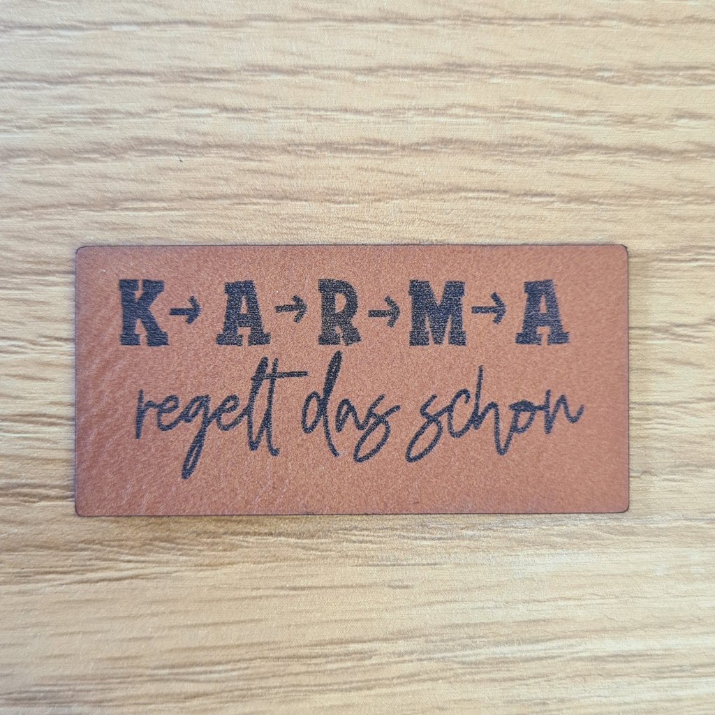 Rechteckiges braunes Kunstleder-Label mit dem Spruch „Karma regelt das schon“, ca. 5 x 2,5 cm, veganes Leder-Patch für entspannte Mode, laser-graviert bei Schnuckidu