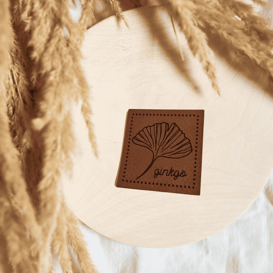 Quadratisches braunes Kunstleder-Label mit einem eleganten Ginkgo-Blatt-Motiv, 4 x 4 cm, veganes Nählabel für zeitlose Kleidung und edle Accessoires, laser-graviert bei Schnuckidu