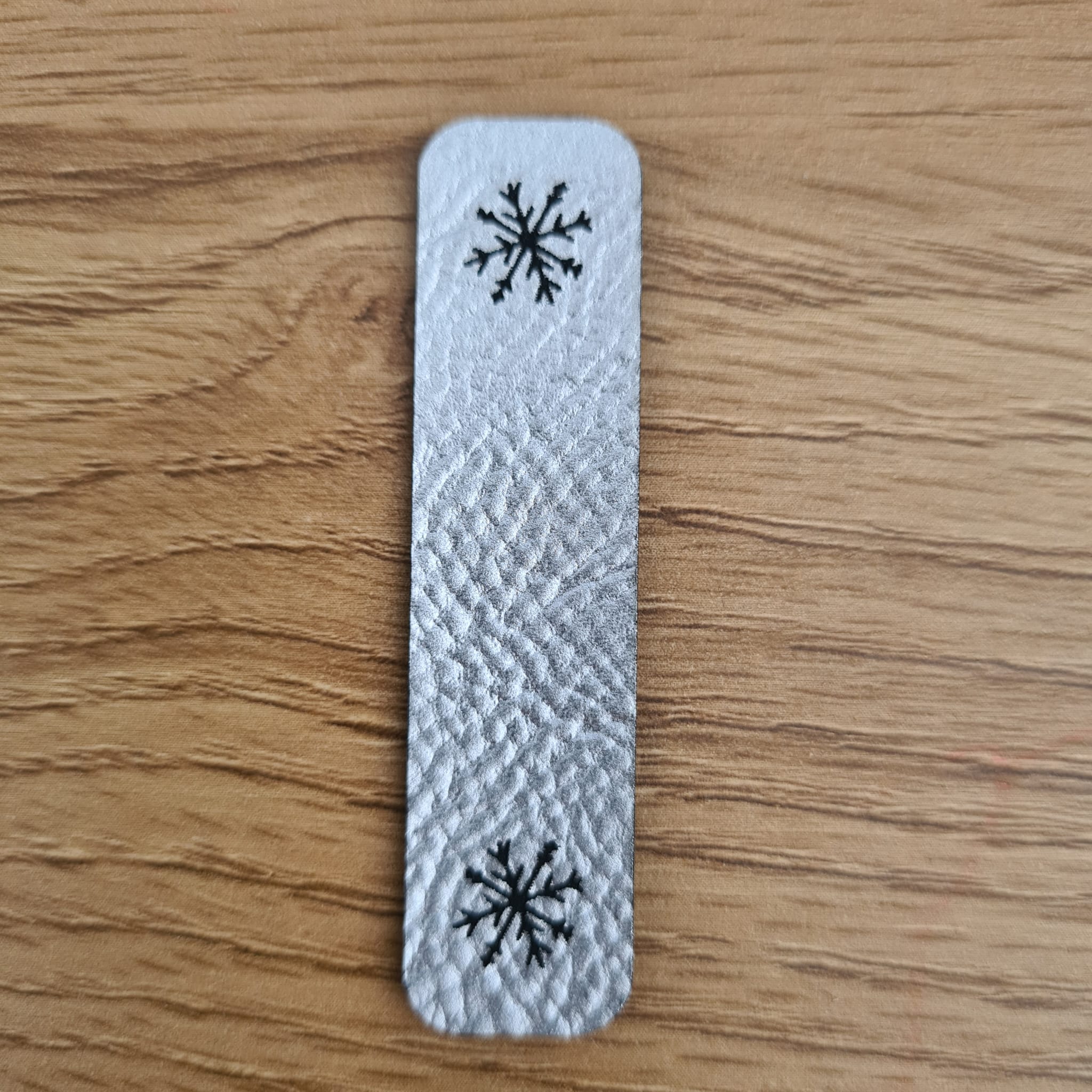 Längliches silbernes Kunstleder-Label „Schneeflocke“, 6 x 1,5 cm, glänzende Optik, veganes Nählabel für Winter-Kleidung, laser-graviert bei Schnuckidu