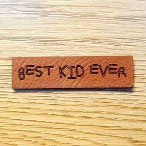 Schmales braunes Kunstleder-Label mit dem Schriftzug „BEST KID EVER“, ca. 5 x 1,3 cm, veganes Leder-Patch für Kinderkleidung, laser-graviert bei Schnuckidu