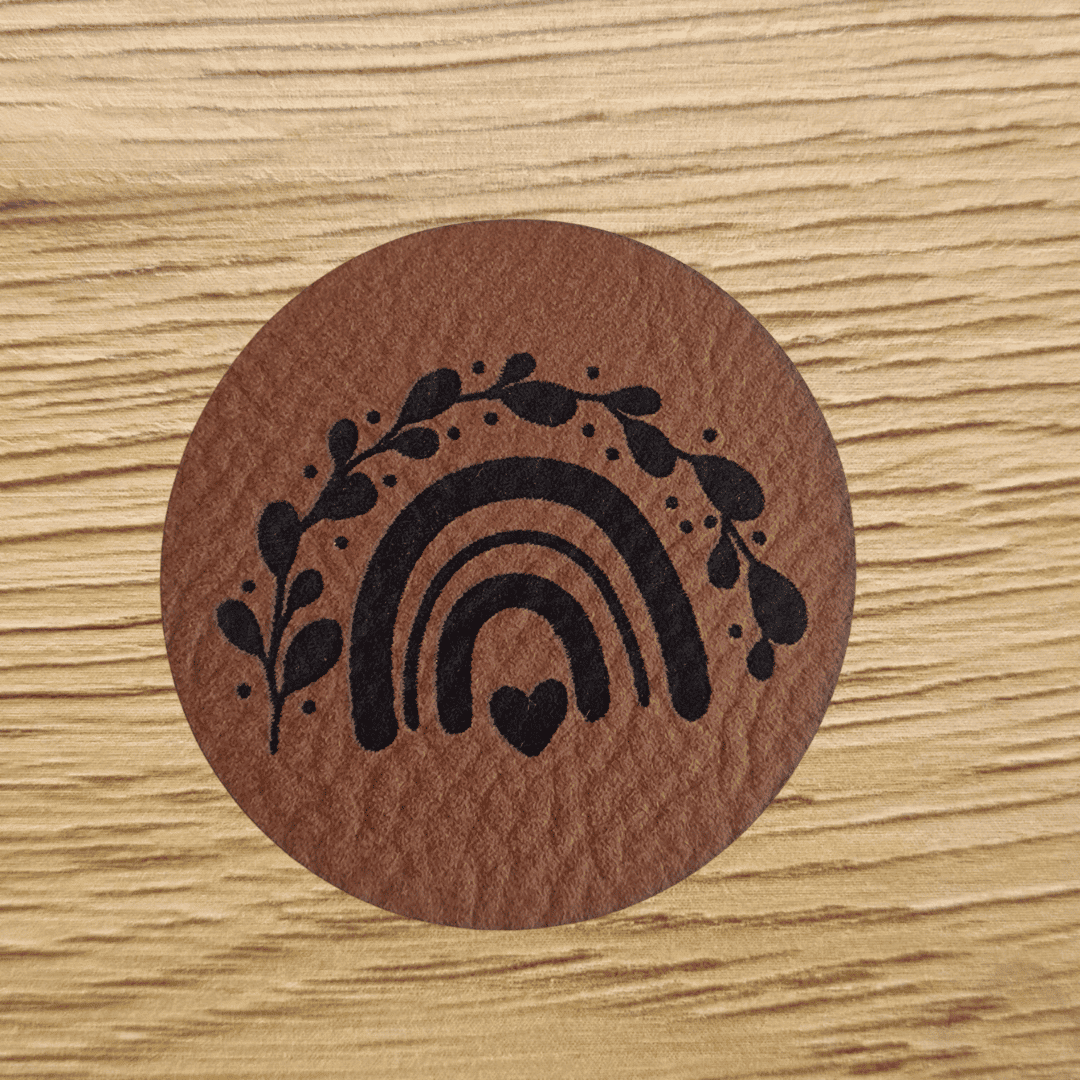 Rundes braunes Kunstleder-Label mit einem gravierten Regenbogen, 4 cm Durchmesser, veganes Nählabel für Kinderkleidung und Accessoires, laser-graviert bei Schnuckidu.