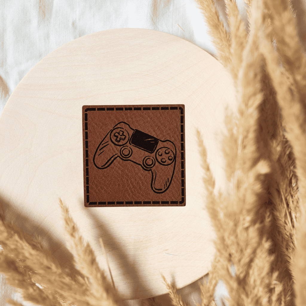 Quadratisches braunes Kunstleder-Label mit Gaming-Controller-Motiv, 4 x 4 cm, veganes Nählabel für Gamer und Kinderkleidung, laser-graviert bei Schnuckidu.