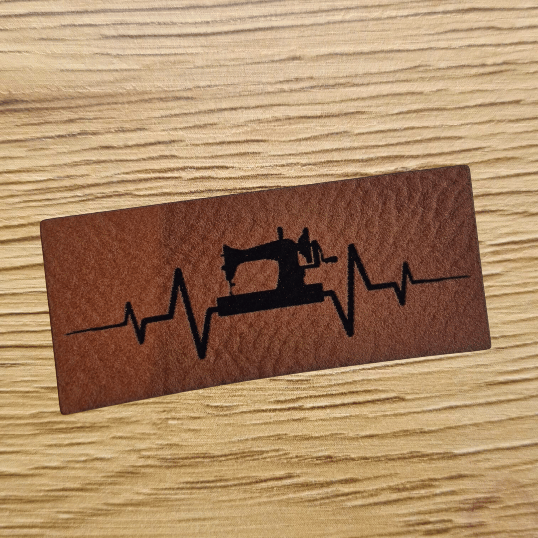 Schmales braunes Kunstleder-Label mit Nähmaschinen-Frequenz-Motiv, ca. 5 x 2,1 cm, veganes Leder-Patch für Näh-Fans, laser-graviert bei Schnuckidu