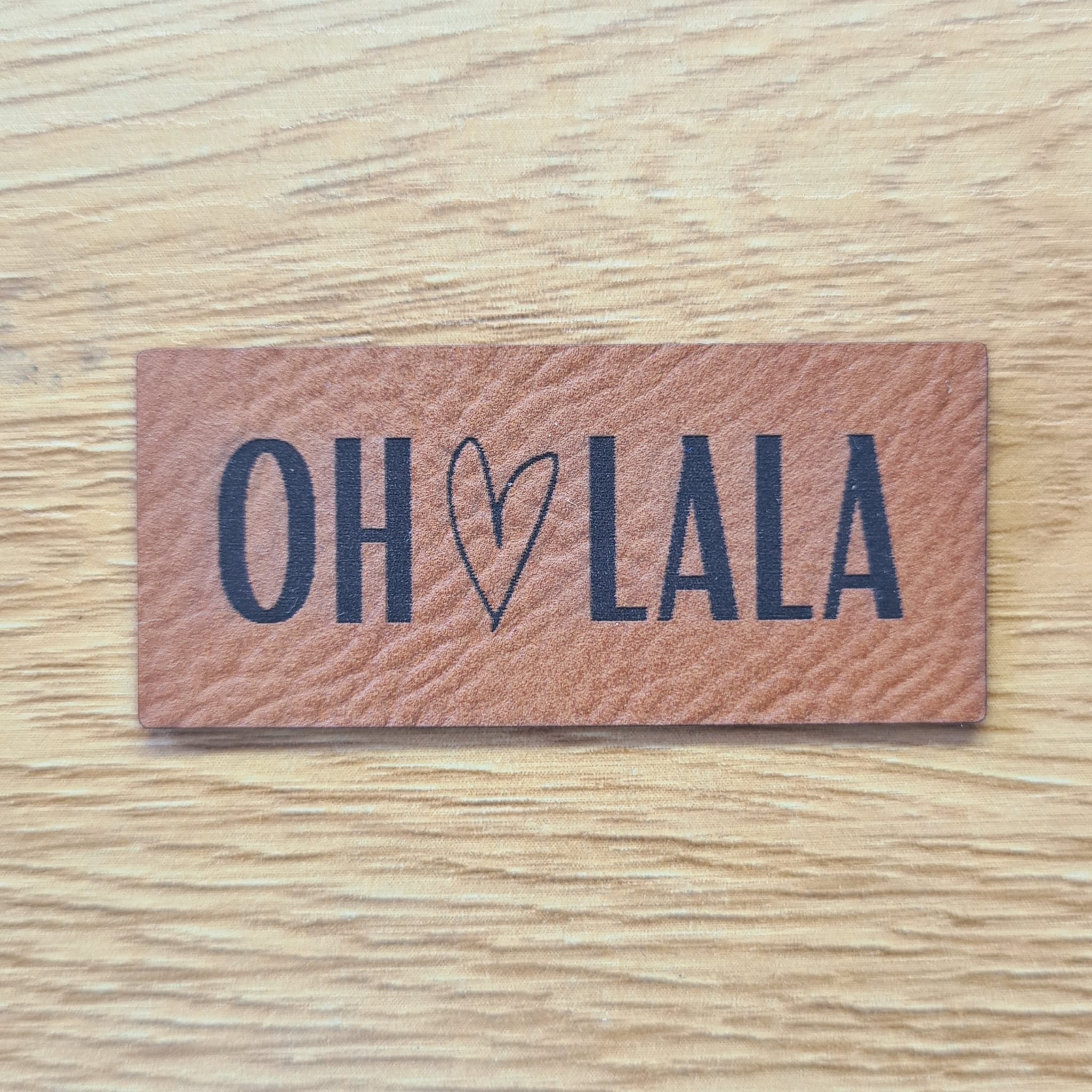 Rechteckiges braunes Kunstleder-Label mit dem gravierten Schriftzug „Oh lala“, 5,0 x 2,0 cm, veganes Nählabel für Kleidung und Accessoires, laser-graviert bei Schnuckidu.