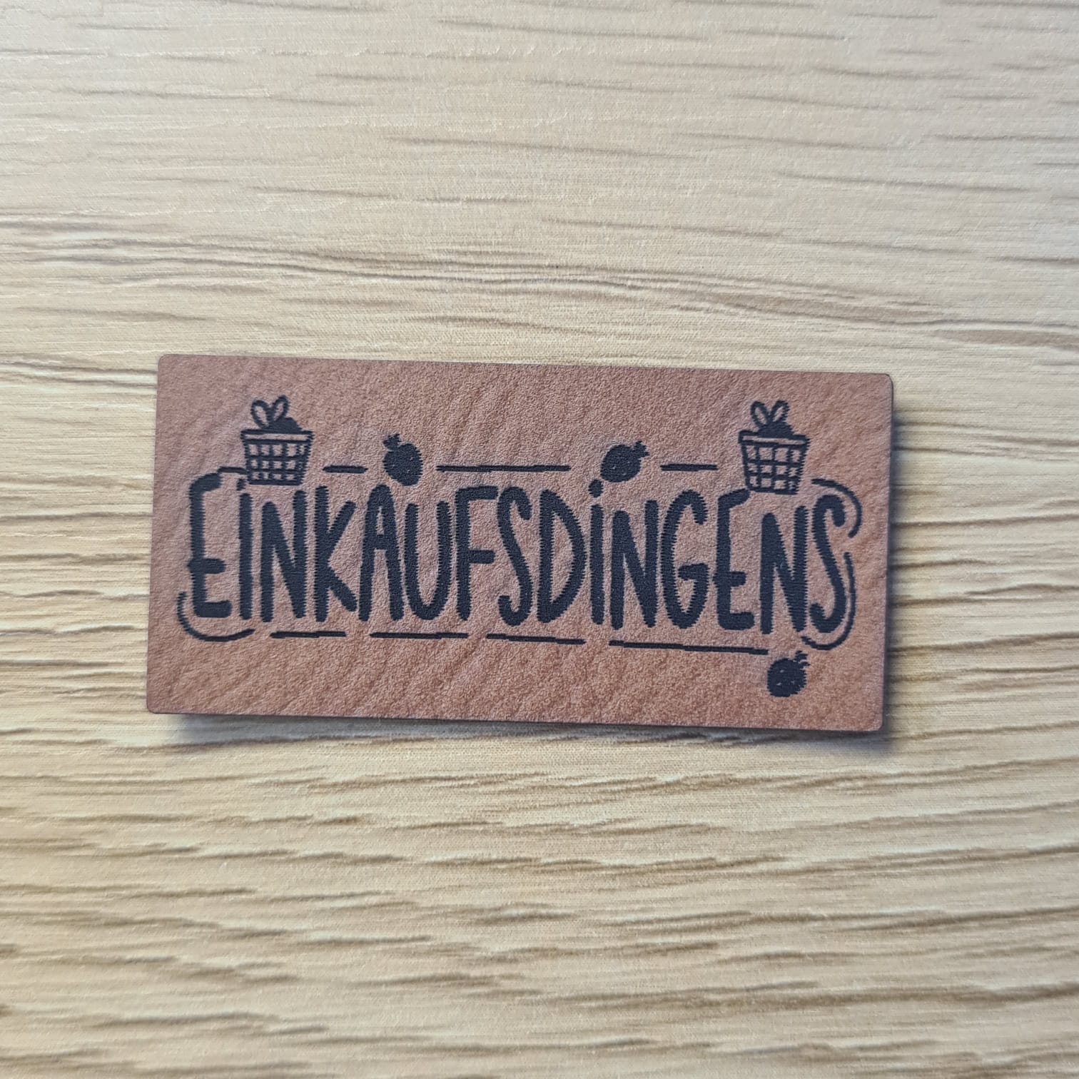 Schnuckidu Kunstleder Nählabel in Braun Querformat mit Schriftzug Einkaufsdingens und Einkaufsbeutel-Motiven.