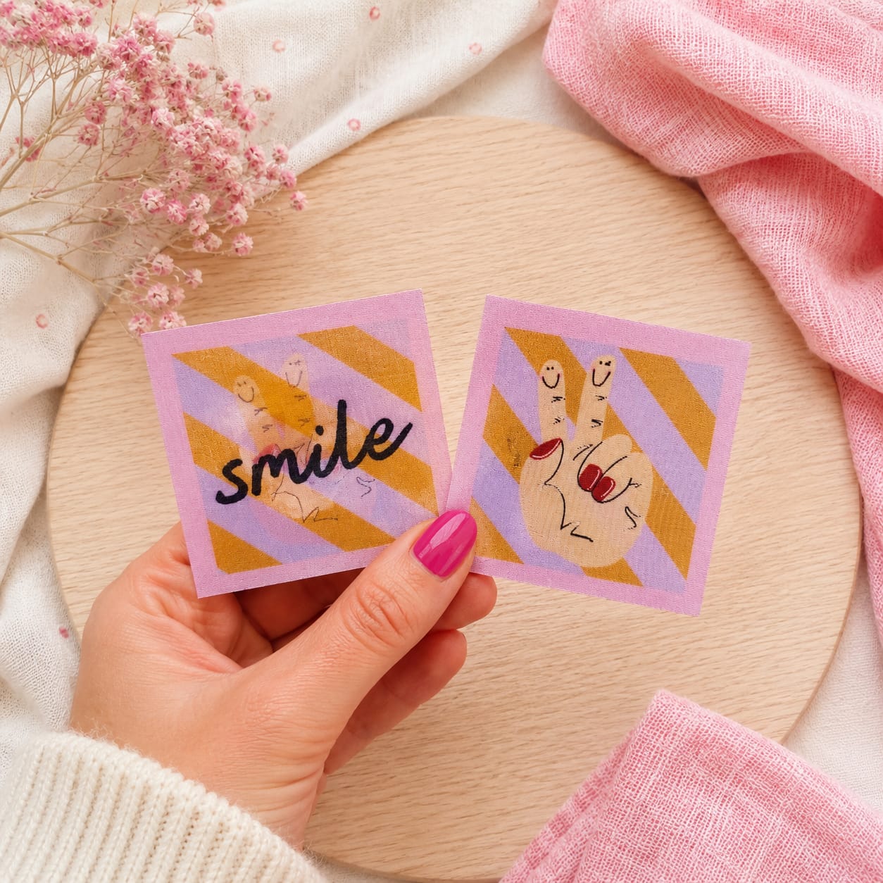 Quadratischer Flippatch Aufnäher von Cherry Picking mit Lentikular-Wackelbild-Effekt wechselnd zwischen dem Schriftzug smile und einer gezeichneten Peace-Hand mit aufgemalten Smileys auf den Fingern vor violett-gold gestreiftem Grund.