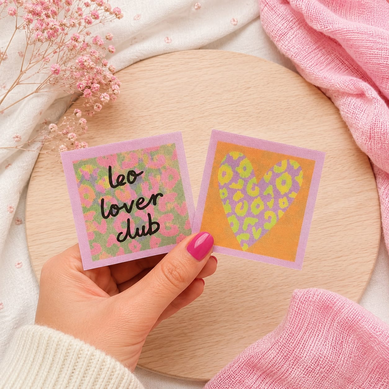 Quadratischer Flippatch Aufnäher von Cherry Picking mit Lentikular-Wackelbild-Effekt wechselnd zwischen dem Schriftzug leo lover club auf rosa-grünem Leopardenmuster und einem violett-gelben Herz im Leoparden-Look vor orangefarbenem Grund.