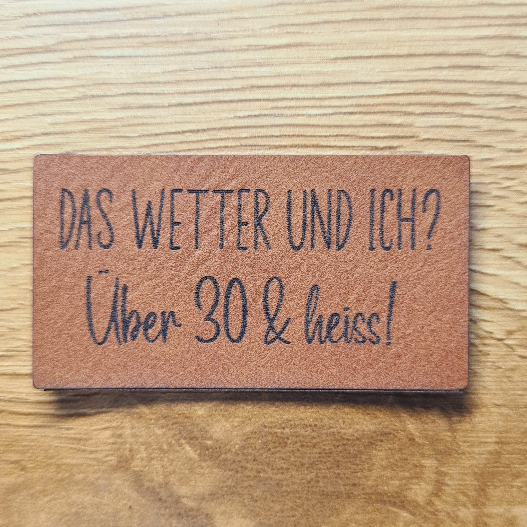 Braunes Kunstleder-Label mit dem Spruch „Das Wetter und ich? Über 30 & heiss“, ca. 5 x 2,6 cm, veganes Leder-Patch, laser-graviert bei Schnuckidu