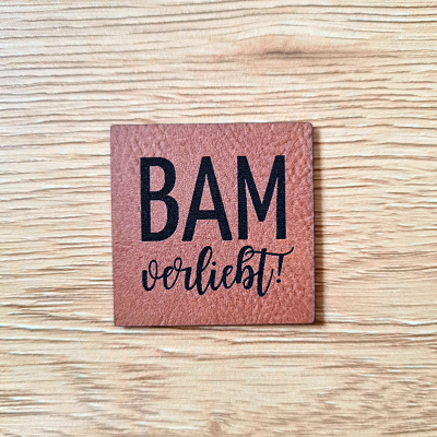 Quadratisches braunes Kunstleder-Label mit dem Schriftzug „BAM verliebt“, 4 x 4 cm, veganes Nählabel mit Herz-Motiv, laser-graviert bei Schnuckidu.