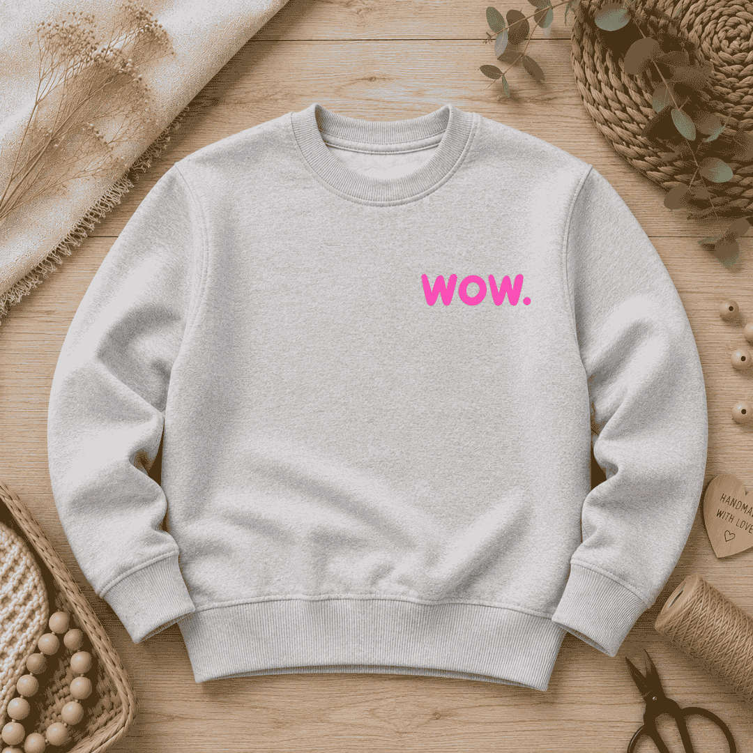 Samtiges Flock-Patch mit dem markanten Schriftzug "wow." in leuchtendem Neon-Pink, aufgebügelt auf der Brust eines hellgrauen Sweatshirts.