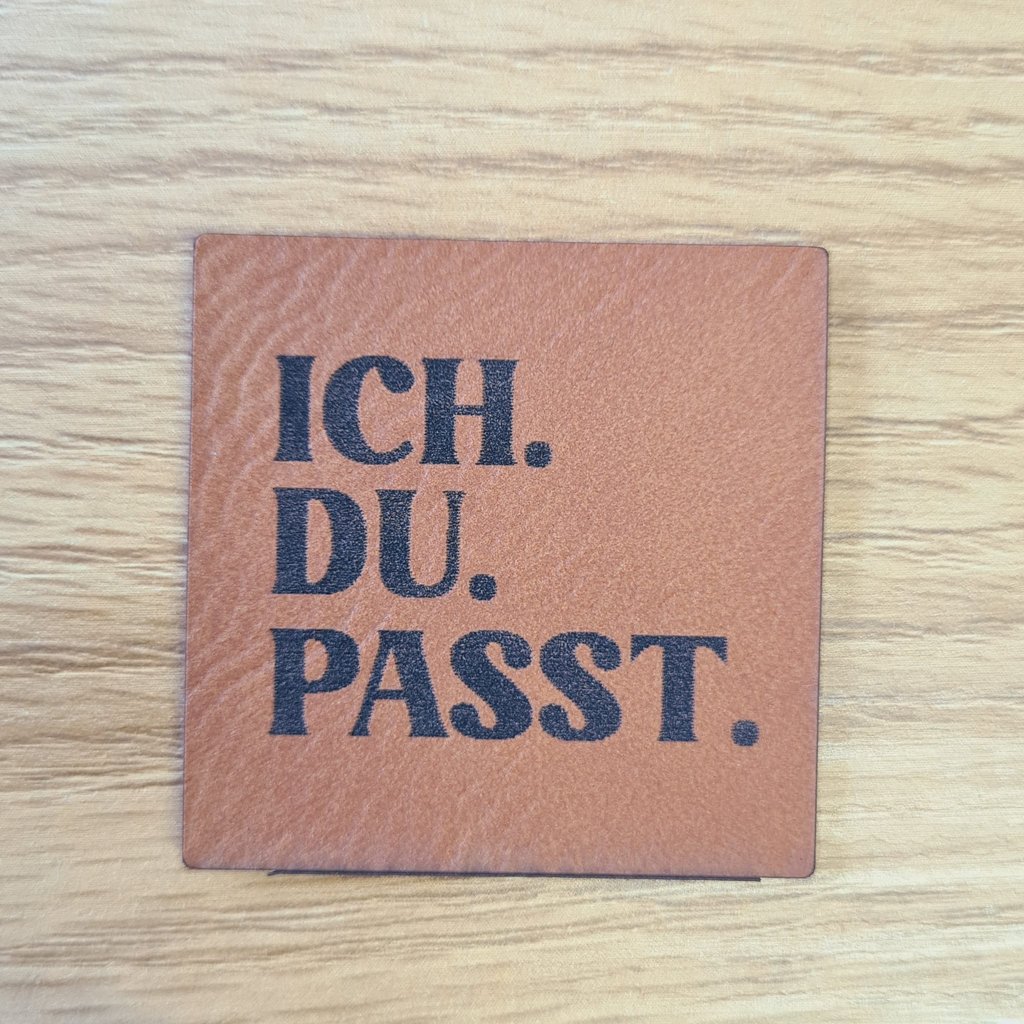 Quadratisches braunes Kunstleder-Label mit dem Spruch „ICH.DU.PASST.“, ca. 4 x 4 cm, veganes Leder-Patch für Freundschafts- und Partnerprojekte, laser-graviert bei Schnuckidu