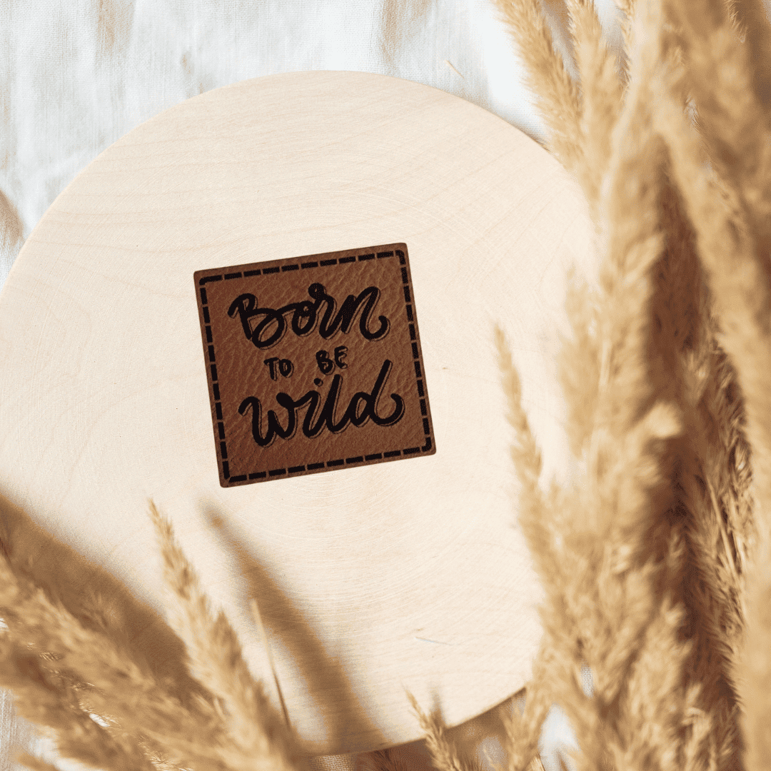 Quadratisches braunes Kunstleder-Label mit dem Schriftzug „Born to be Wild“, 4 x 4 cm, veganes Nählabel für coole Kinderkleidung und Abenteurer, laser-graviert bei Schnuckidu.