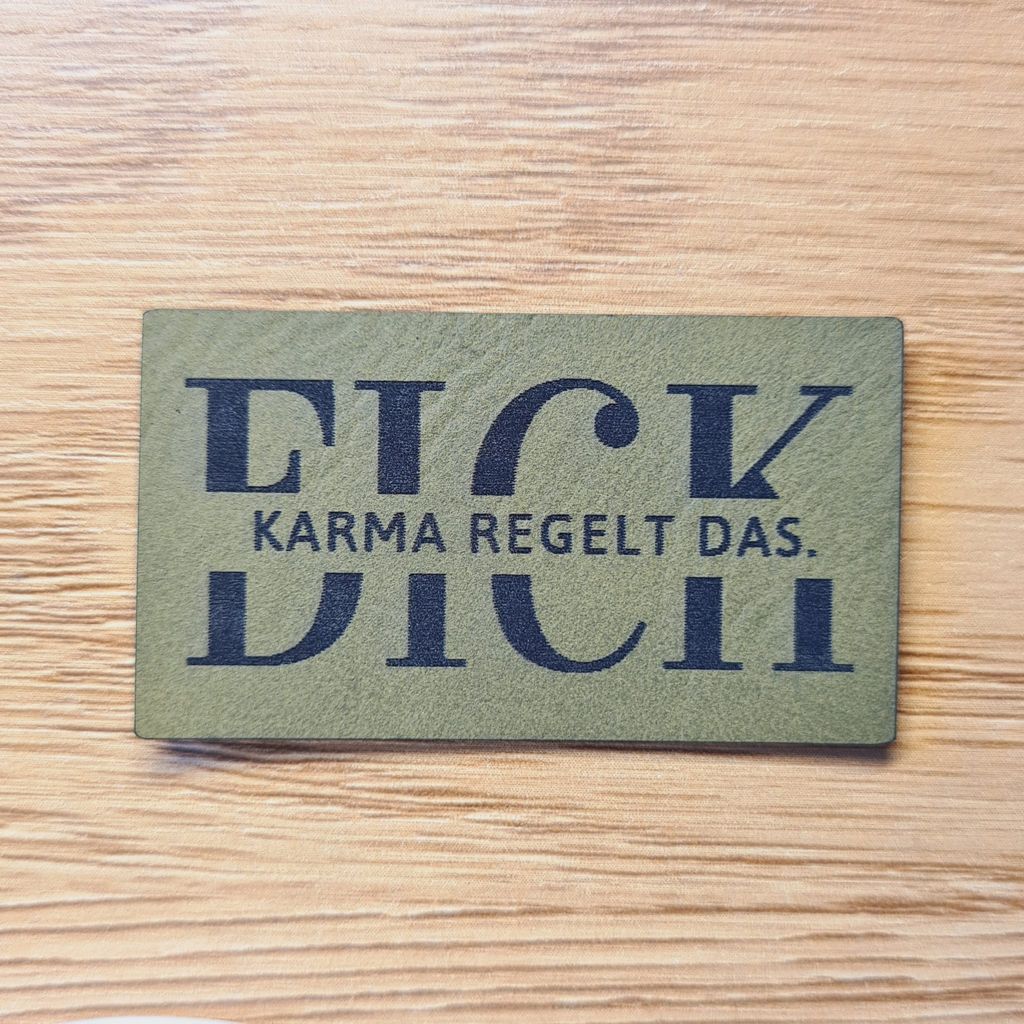 Rechteckiges olivegrünes Kunstleder-Label mit dem provokanten Spruch „FICK DICH - Karma regelt das“, 5 x 2,8 cm, veganes Nählabel für selbstbewusste Statement-Kleidung, laser-graviert bei Schnuckidu.