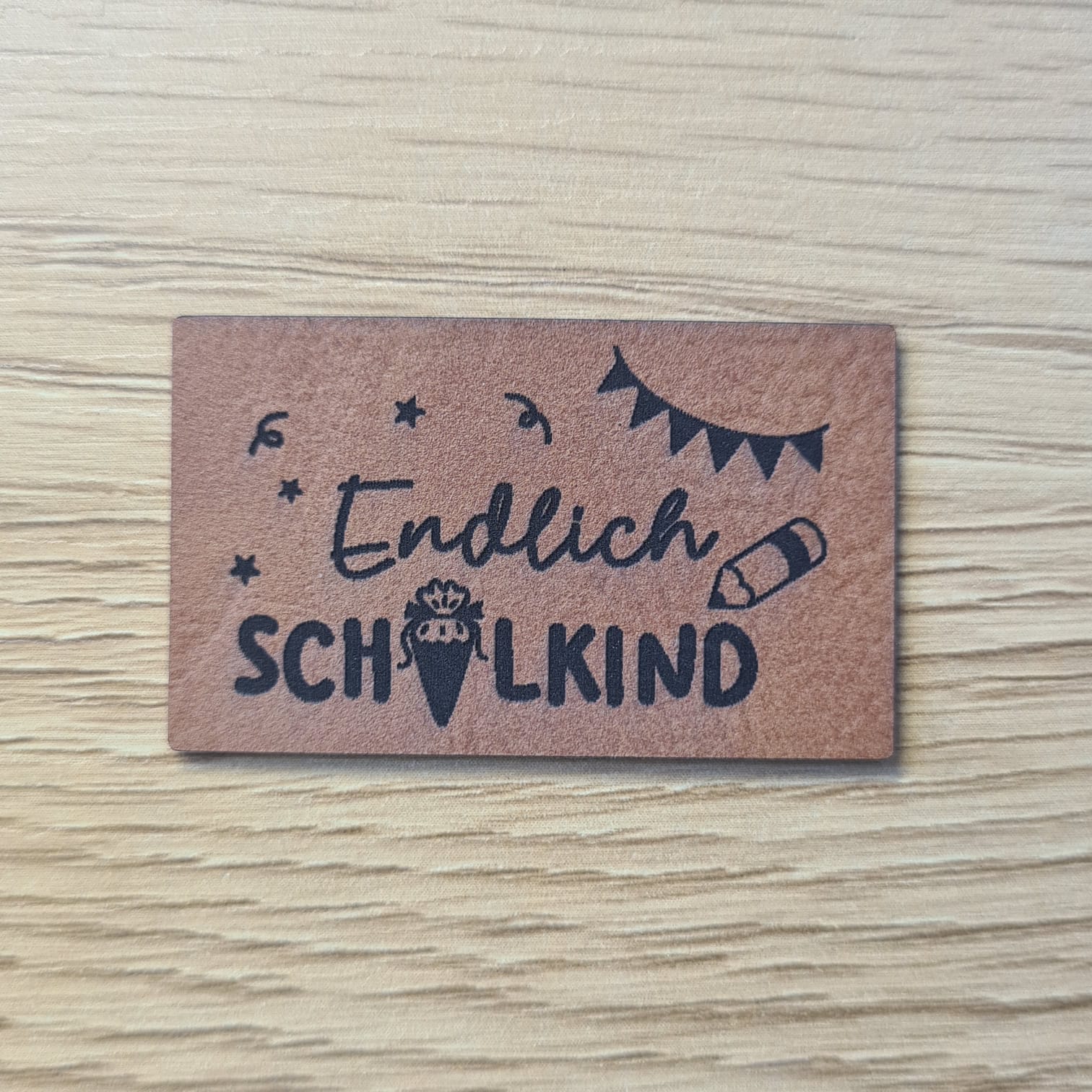 Schnuckidu Kunstleder Nählabel in Braun mit der Aufschrift Endlich Schulkind, Schultüte, Stift und Wimpelkette.