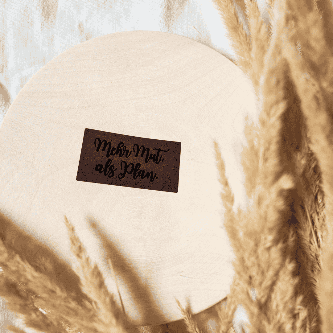 Rechteckiges dunkelbraunes Kunstleder-Label mit dem Spruch „Mehr Mut als Plan“, ca. 4,3 x 2,2 cm, veganes Leder-Patch für kreative Nähprojekte, laser-graviert bei Schnuckidu