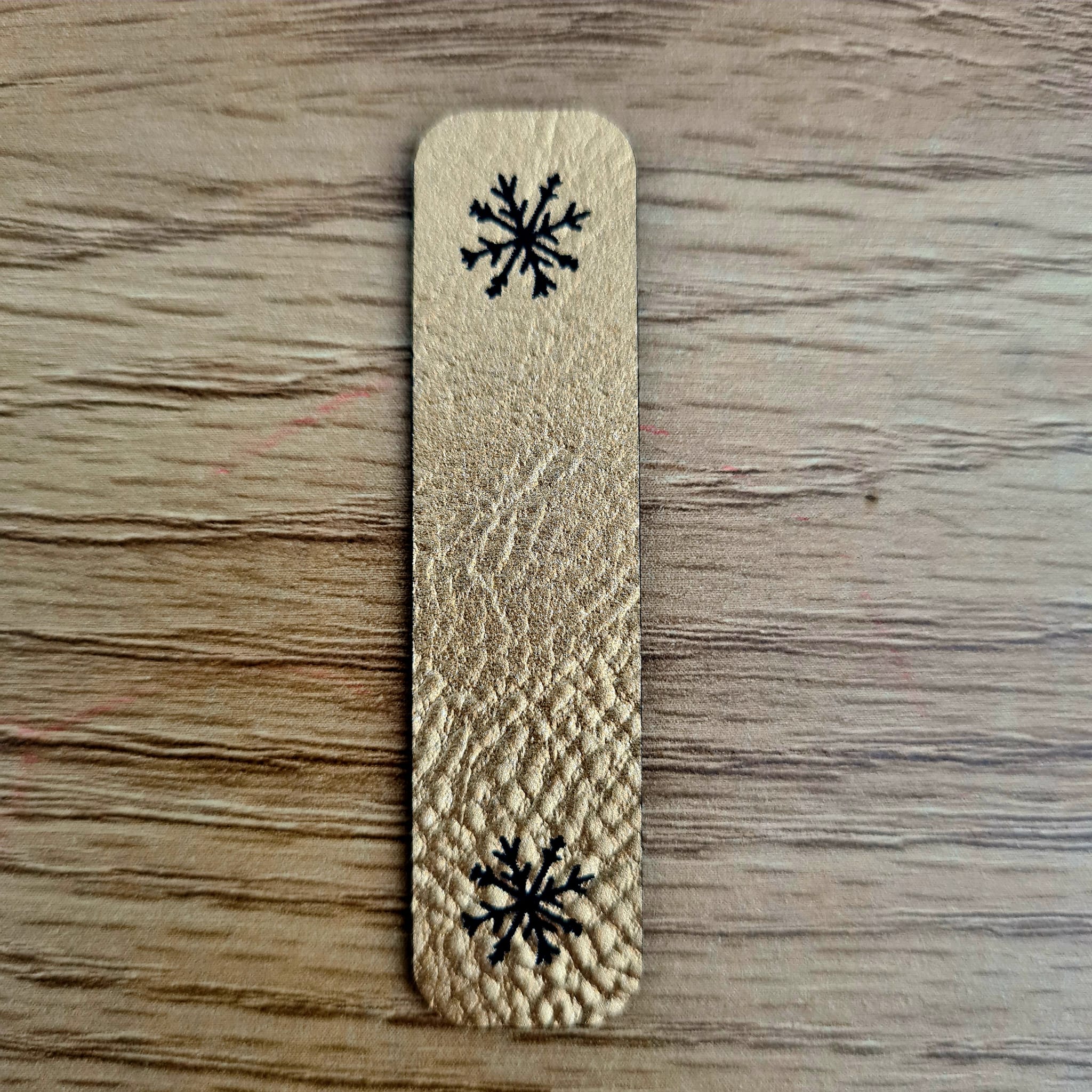 Längliches goldenes Kunstleder-Label „Schneeflocke“, 6 x 1,5 cm, glänzende Optik, veganes Nählabel für Winter-Accessoires, laser-graviert bei Schnuckidu