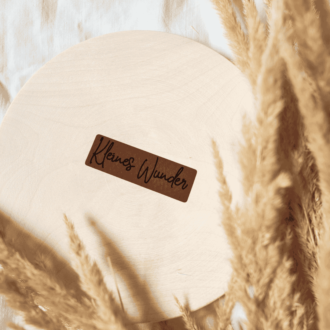 Schmales, rechteckiges braunes Kunstleder-Label mit dem Schriftzug „Kleines Wunder“, 4,7 x 1,7 cm, veganes Nählabel für Babykleidung und Erstlingsausstattung, laser-graviert bei Schnuckidu