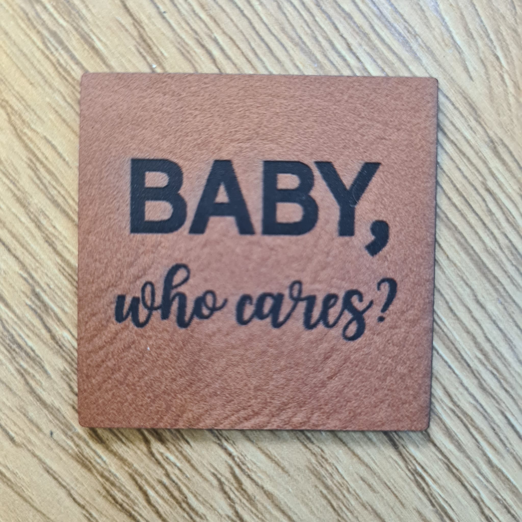Quadratisches braunes Kunstleder-Label mit Spruch „Baby who cares?“, 4 x 4 cm, veganes Patch für Kindermode, laser-graviert bei Schnuckidu
