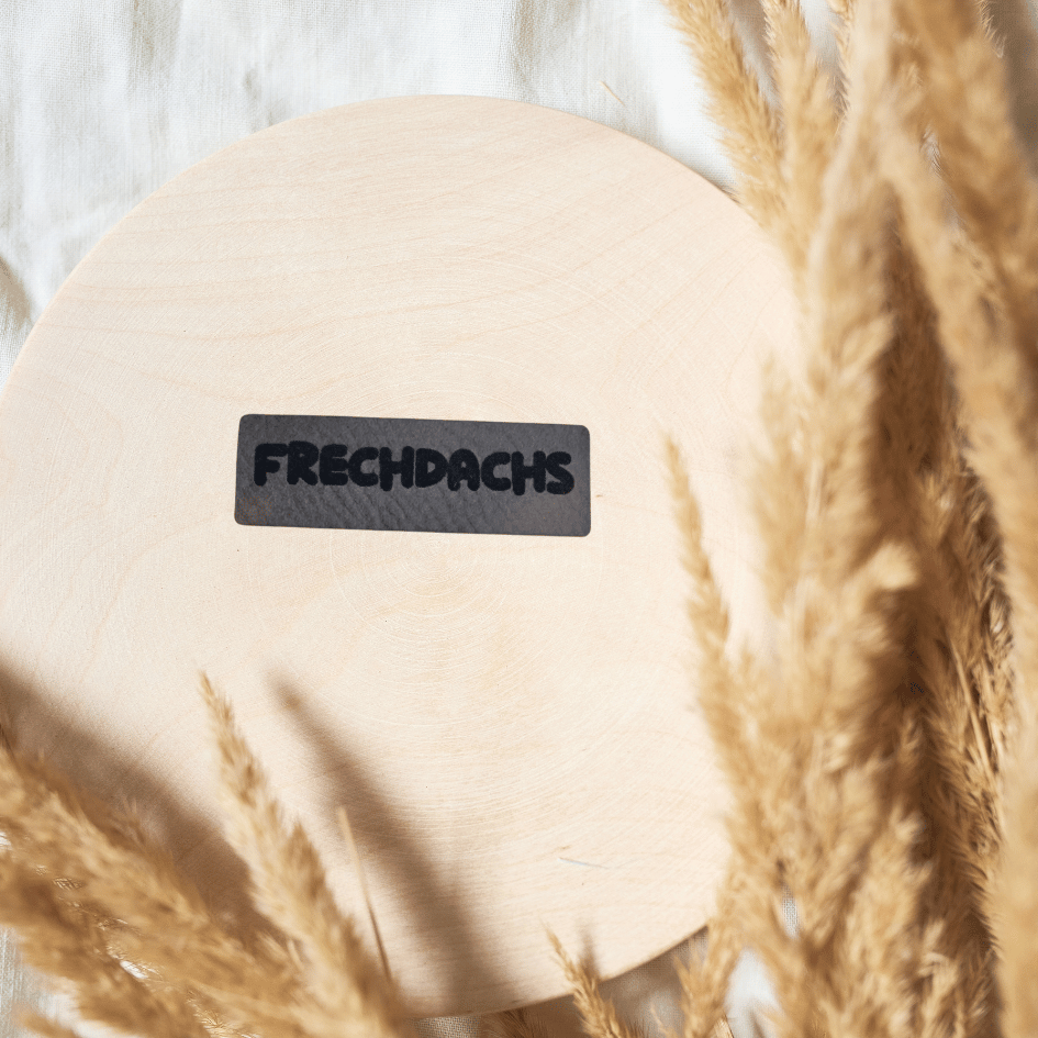 Schmales rechteckiges graues Kunstleder-Label mit dem Schriftzug „Frechdachs“, 4,2 x 1,3 cm, veganes Nählabel für Kinderkleidung, laser-graviert bei Schnuckidu.