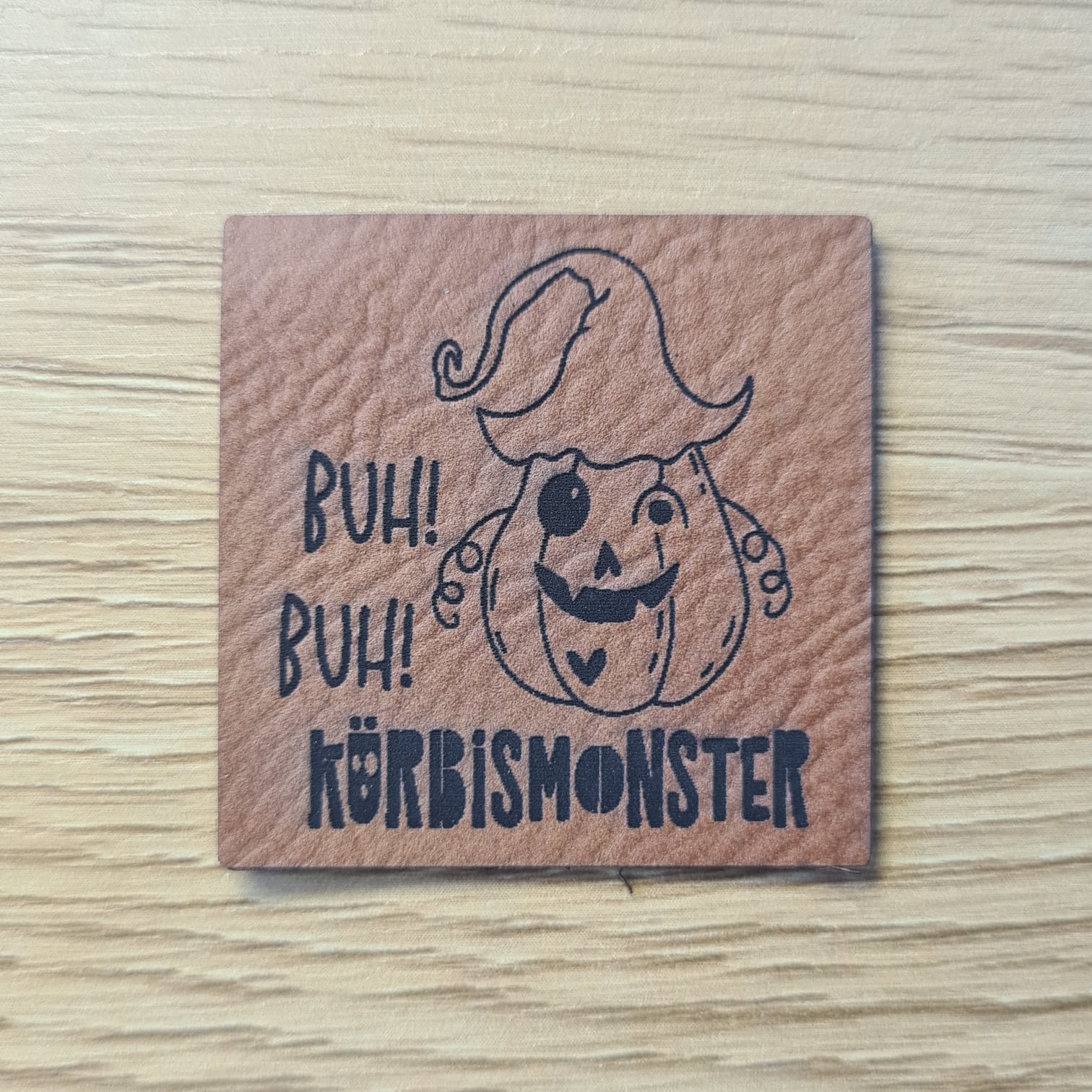 Schnuckidu Kunstleder Nählabel in Braun quadratisch mit Kürbismonster im Hexenhut und Schriftzug Buh! Buh! Kürbismonster.