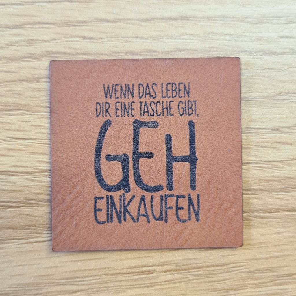 Quadratisches braunes Kunstleder-Label mit dem Spruch „Wenn das Leben dir eine Tasche gibt, geh einkaufen“, ca. 4 x 4 cm, veganes Leder-Patch für Taschen-Projekte, laser-graviert bei Schnuckidu