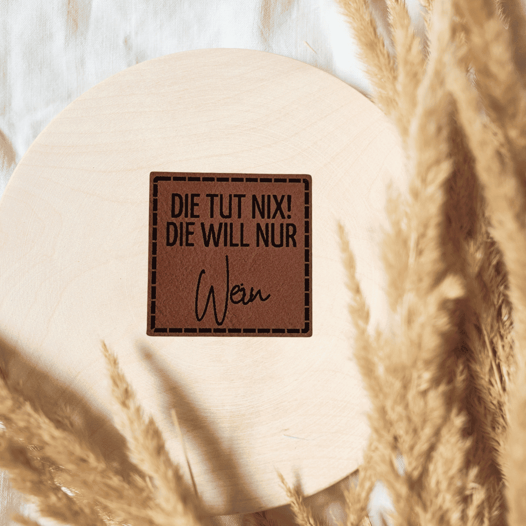 Quadratisches braunes Kunstleder-Label mit dem Schriftzug „Die tut nix“, 4 x 4 cm, veganes Nählabel mit humorvollem Haustier-Statement, laser-graviert bei Schnuckidu.