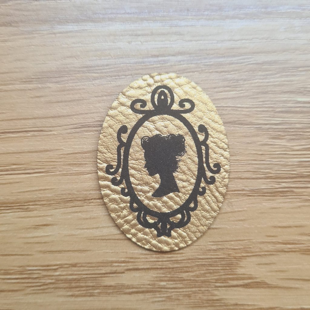 Hochkantiges goldenes Kunstleder-Label mit der Silhouette einer Frau im Spiegel, ca. 3 x 4 cm, veganes Leder-Patch in Metallic-Optik, laser-graviert bei Schnuckidu
