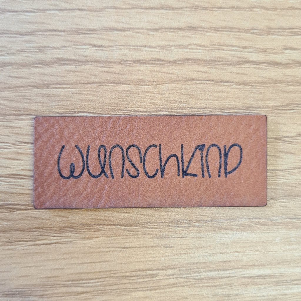 Rechteckiges braunes Kunstleder-Label mit dem Schriftzug „Wunschkind“, ca. 5 x 2 cm, veganes Leder-Patch für Babykleidung und Erstausstattung, laser-graviert bei Schnuckidu