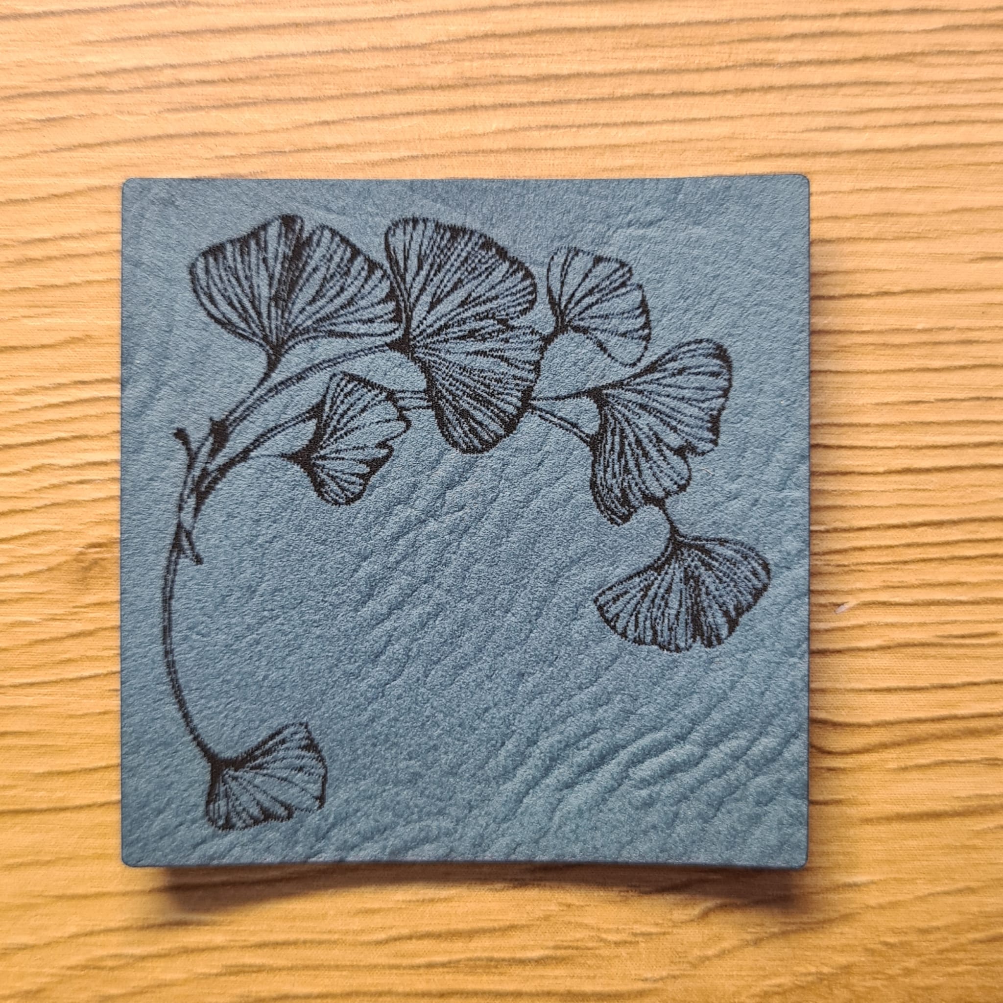 Kunstleder-Label „Ginkgo“, 4 x 4 cm, florales Design in Petrol, vegan, laser-graviert bei Schnuckidu, stilvolles Detail für Kleidung.